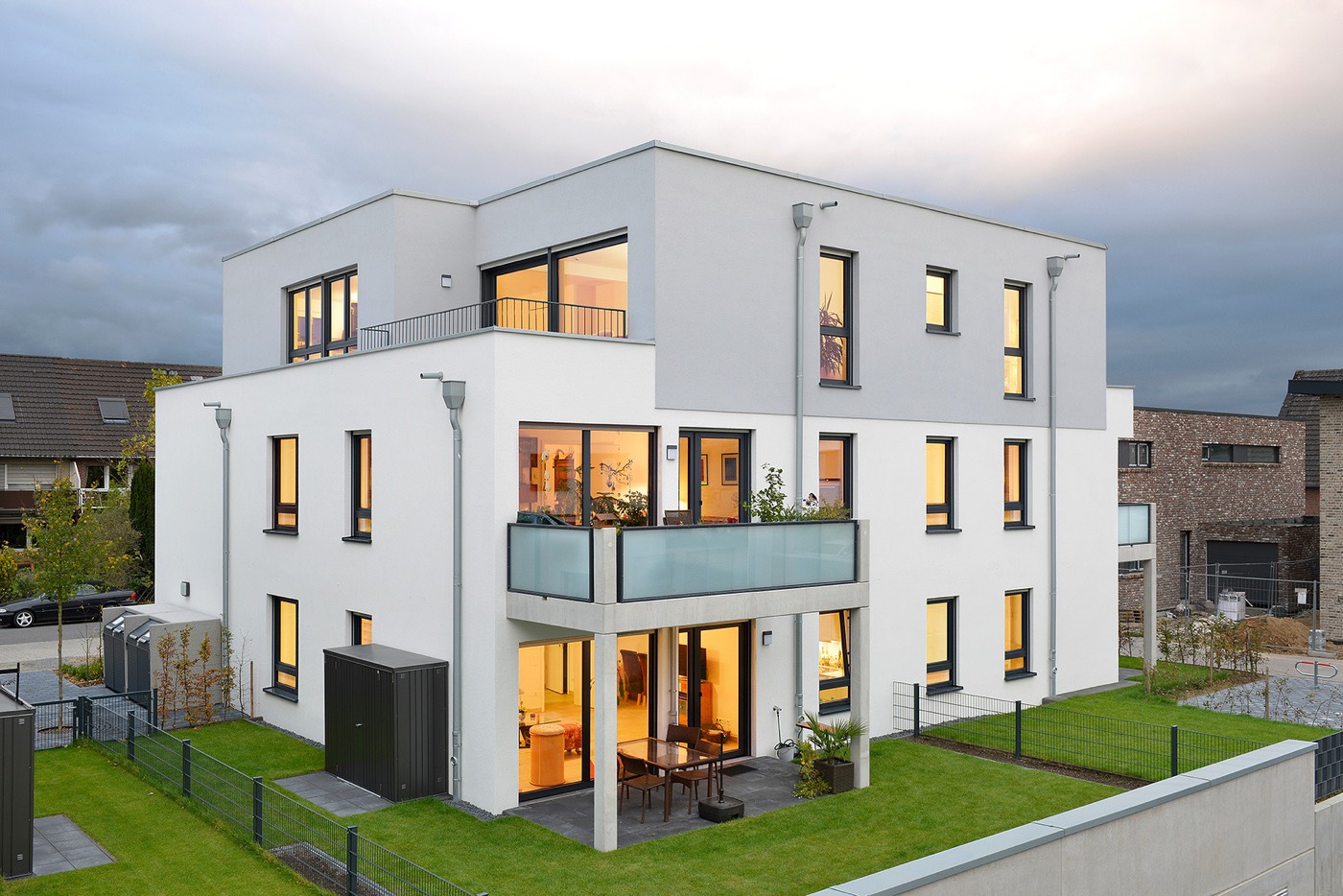 Modernes Mehrfamilienhaus mit beleuchteten Fenstern in der Abenddämmerung